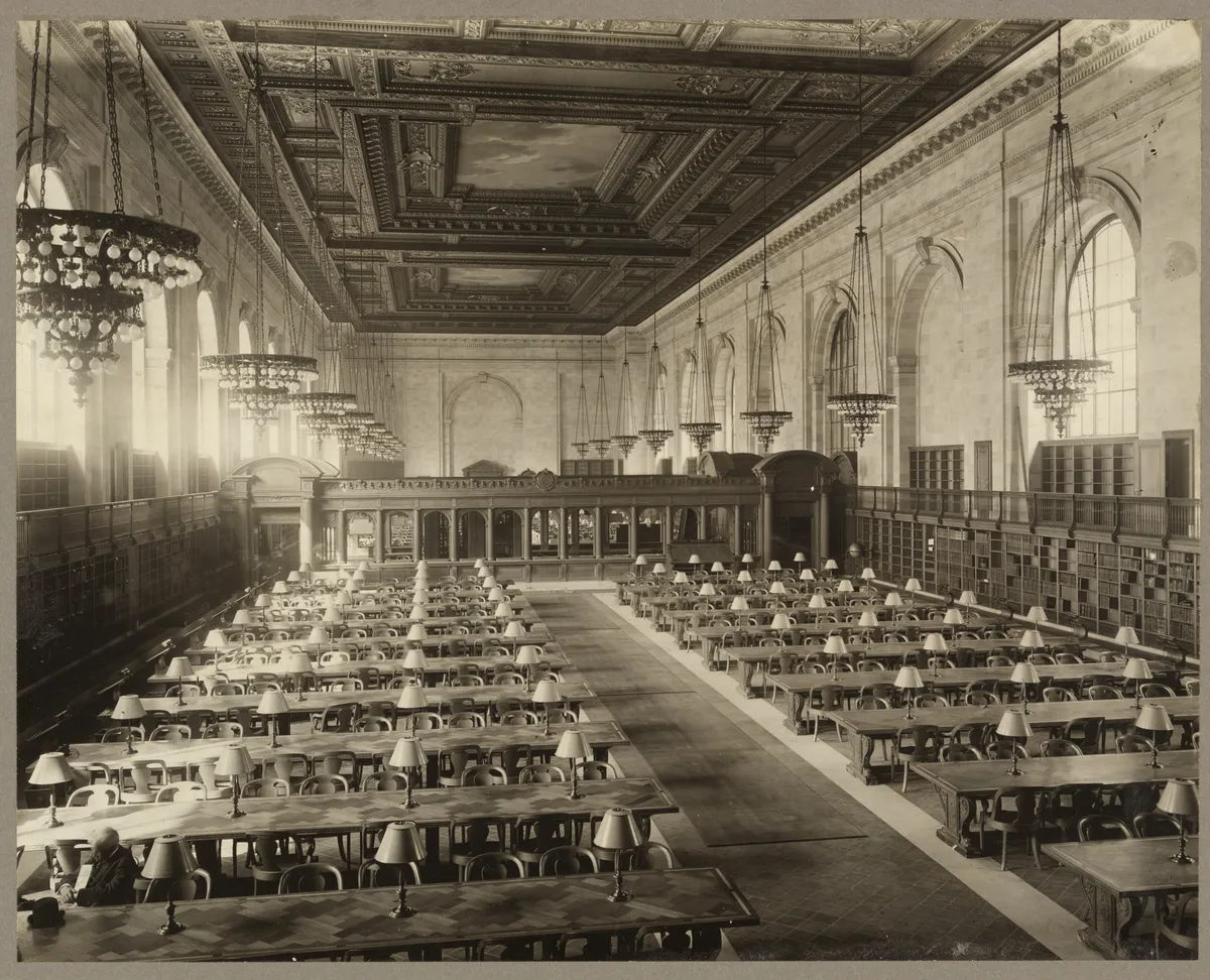 The Main Reading Room of the New York Public Library: long oak tables with reading lamps beneath a painted ceiling.