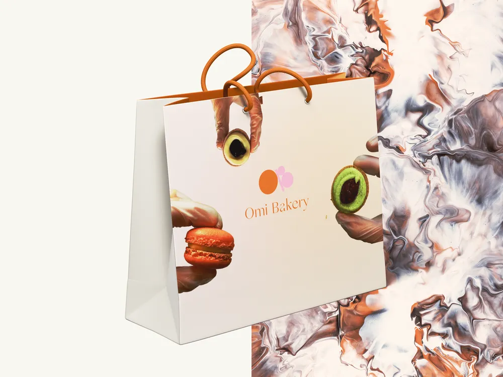 An Omi Bakery paper shopping bag, with hands holding macarons.