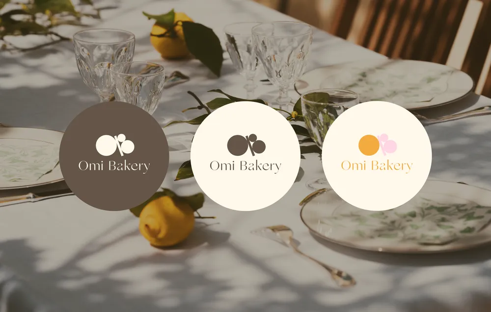 Round Omi Bakery logo badges in brown, cream and orange on a set table.