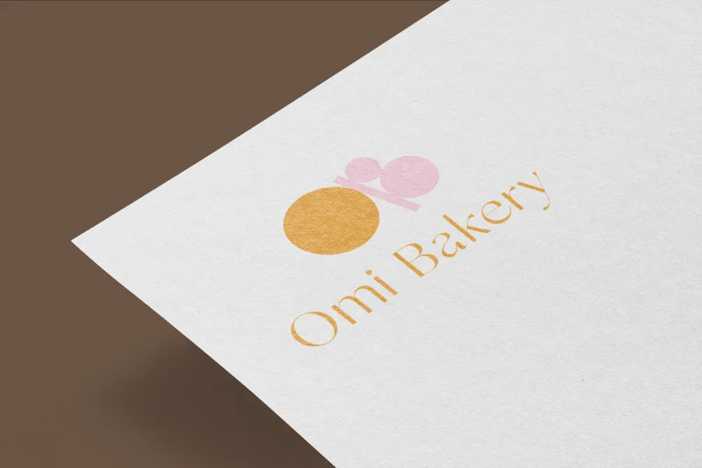 The Omi Bakery logo embossed on white card against a brown ground.