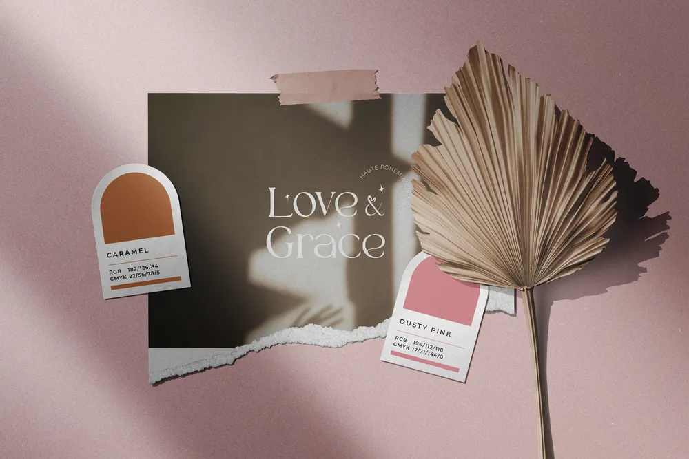 Love & Grace color swatches and a business card pinned beside a dried palm leaf on a pink wall.