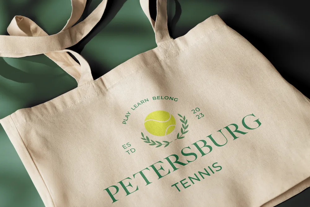 A canvas tote bag printed with the Petersburg Tennis crest, on a dark green ground.
