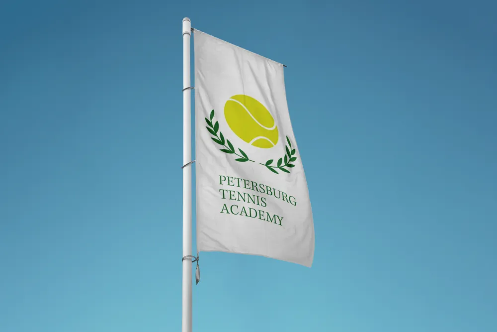 A white flag with the Petersburg Tennis Academy crest against a blue sky.